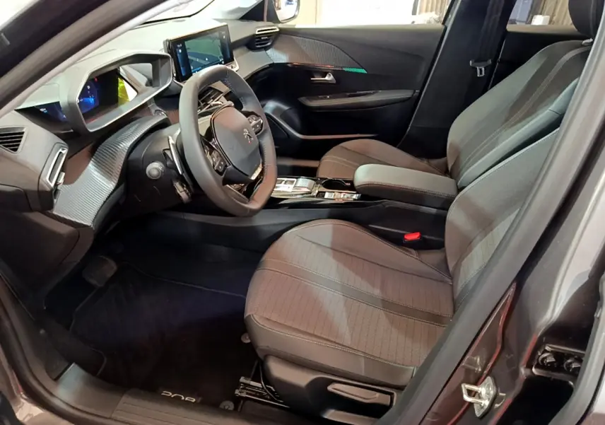Intérieur avant droit du Peugeot 208 gris foncé 2022, volant cuir, écran tactile et sièges tissu gris.