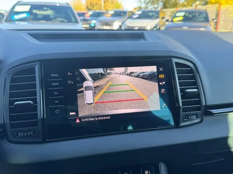 Écran tactile intérieur montrant la caméra de recul du Skoda Karoq gris, avec lignes de guidage colorées.