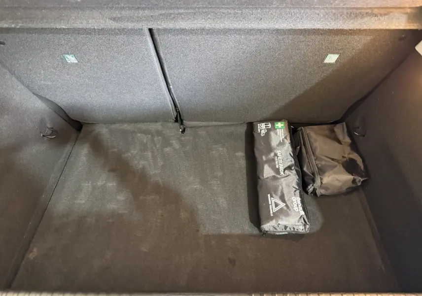 Coffre noir de Renault Clio Business blanc, vue plongeante montrant un kit de sécurité et un sac de rangement.