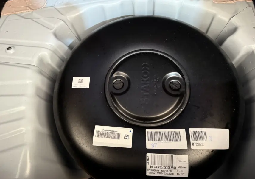 Vue rapprochée du réservoir GPL noir dans le coffre blanc d'une Renault Clio Business TCe 100 GPL 2023.