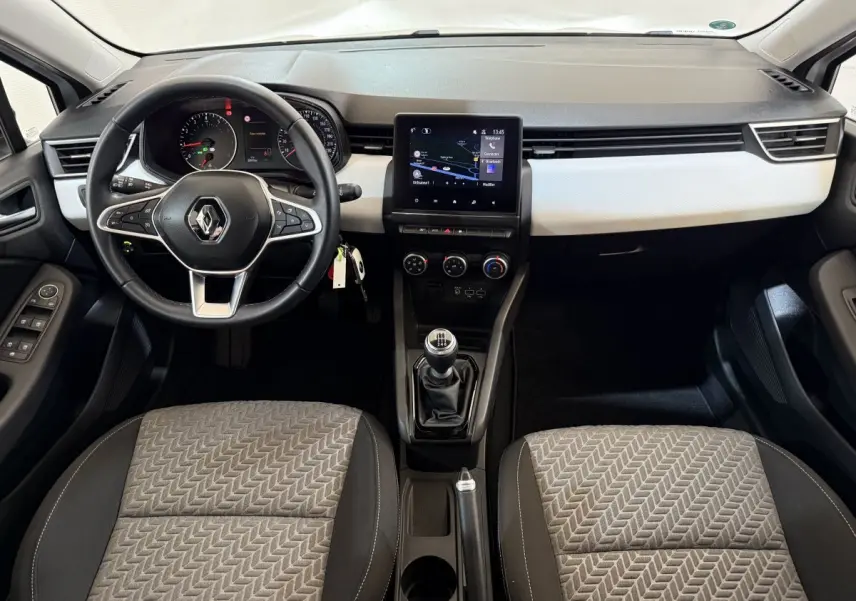 Vue intérieure avant de la Renault Clio Business 2023, tableau de bord noir et blanc avec écran tactile central et volant multifonctions.