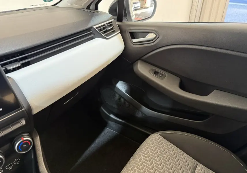 Intérieur côté passager de la Renault Clio Business blanc, avec tableau de bord clair et porte noire.