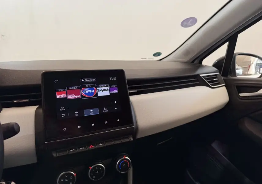 Tableau de bord de Renault Clio Business blanc, vue intérieure côté passager avec écran tactile central allumé.