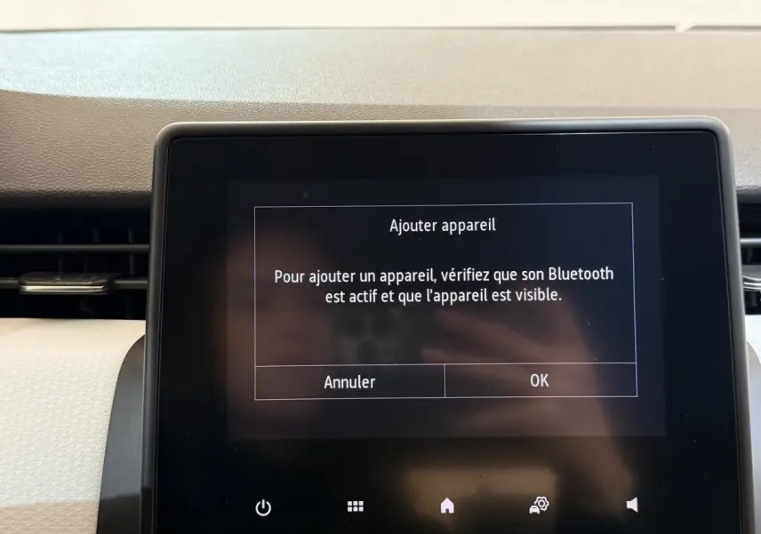 Écran tactile central du tableau de bord de la Renault Clio Business blanc, affichant un message Bluetooth.