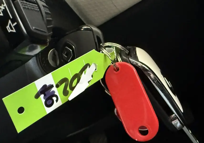 Clé de contact Renault Clio Business TCe 100 GPL 2023 avec porte-clés rouge et étiquette verte, vue intérieure rapprochée.