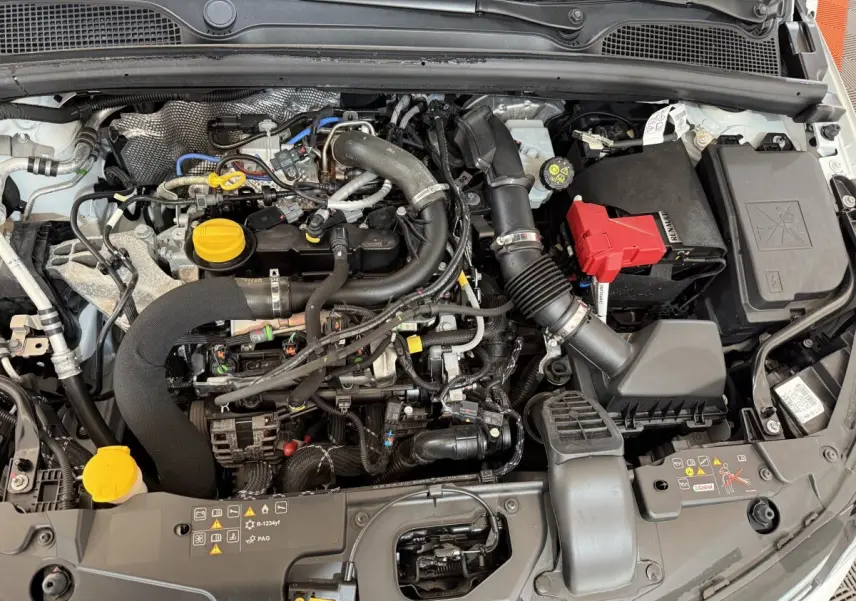 Vue plongeante sur le moteur blanc de la Renault Clio Business TCe 100 GPL 2023 avec bouchons jaunes visibles.