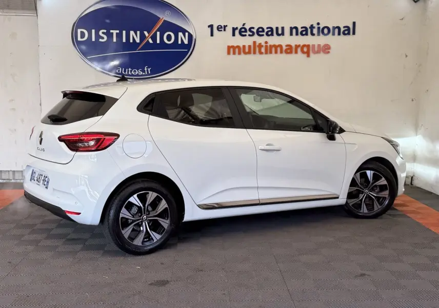 Profil droit d'une Renault Clio Business TCe 100 GPL blanche 2023 avec jantes alliage et toit spoiler noir.