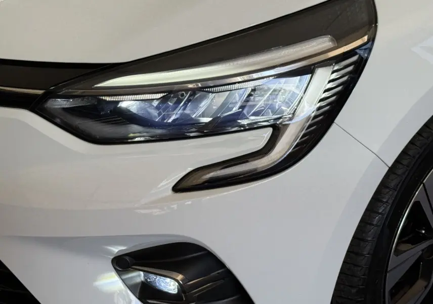 Gros plan sur le phare avant droit blanc de la Renault Clio Business TCe 100 GPL 2023 avec feu LED et partie de la roue visible.