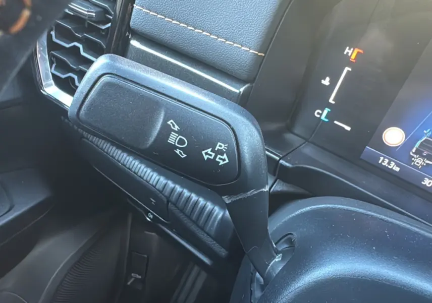Gros plan sur la manette de clignotants et feux du Ford Ranger 2025, intérieur noir avec tableau de bord numérique.