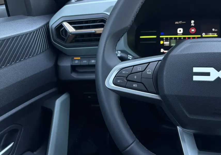 Gros plan sur le volant et le tableau de bord digital du Dacia Duster 2026, intérieur noir avec commandes au volant.