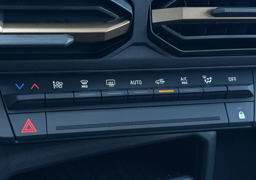 Gros plan sur la console centrale du Dacia Duster 2026 gris, montrant les commandes de climatisation automatique et les boutons fonctionnels.