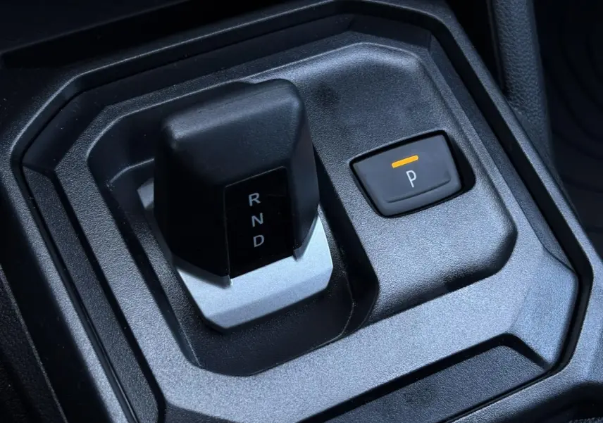 Gros plan sur la commande de boîte automatique et bouton parking du Dacia Duster ECO-G 120 gris intérieur noir.