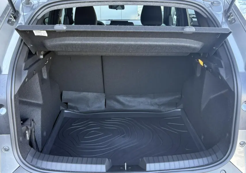 Coffre ouvert vu de l'arrière du Dacia Duster 2026 gris schiste, montrant l'espace de chargement et la protection de sol.