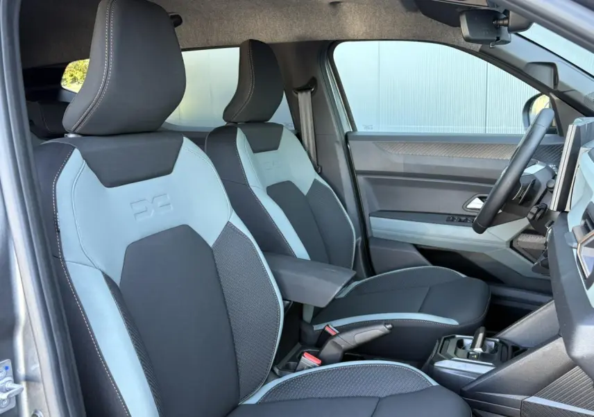 Vue intérieure côté conducteur du Dacia Duster 2026, sièges TEP MicroCloud noirs et gris avec accoudoir central.