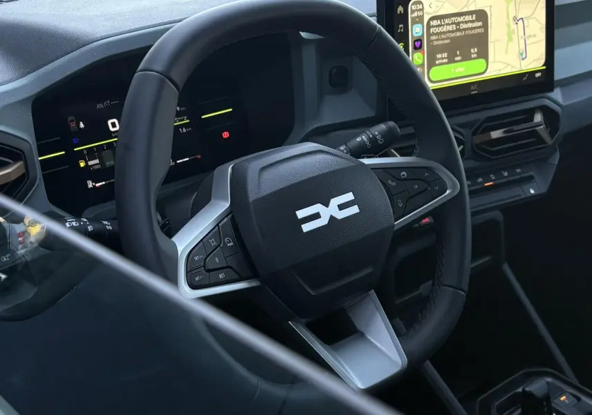 Vue rapprochée de l’intérieur du Dacia Duster 2026, volant multifonction noir avec tableau de bord digital et écran tactile.