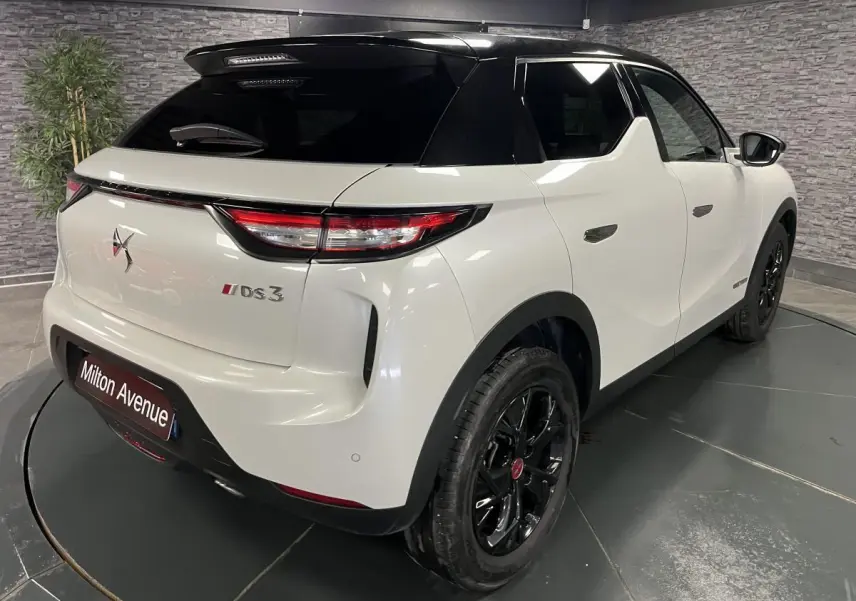 Vue 3/4 arrière droite du DS3 Crossback bi-ton blanc et noir avec jantes noires et becquet de toit noir.