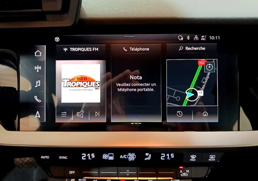 Écran tactile central de l’Audi A3 Business Line 2023 affichant radio, téléphone et navigation, avec commandes climatisation en dessous.