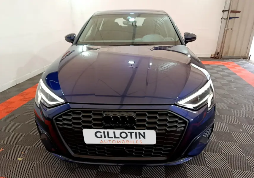 Vue avant d'une Audi A3 35 TFSI bleu profond avec calandre noire et phares LED allumés en intérieur