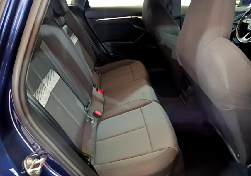 Vue intérieure côté gauche montrant la banquette arrière grise de l'Audi A3 35 TFSI 150 MHEV Business Line bleu 2023.