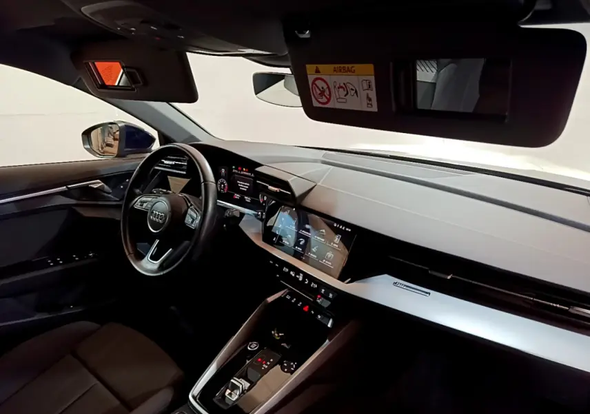 Intérieur de l'Audi A3 35 TFSI 2023 vu côté conducteur, tableau de bord moderne avec écrans tactiles et volant cuir.
