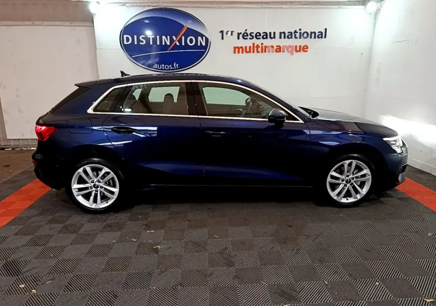 Profil côté gauche d'une Audi A3 bleu foncé 2023 stationnée en intérieur avec jantes alliage argentées visibles.
