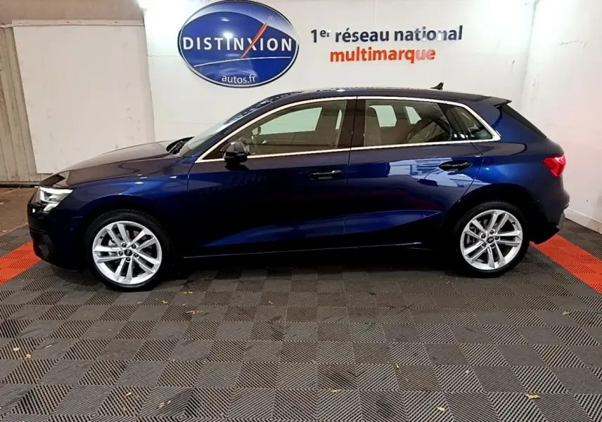 Profil côté gauche d'une Audi A3 bleu foncé 2023 garée en intérieur avec jantes alliage et vitres teintées.