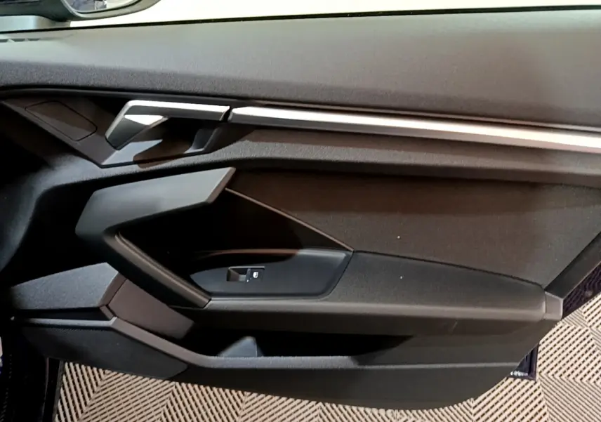 Vue rapprochée de la porte côté gauche de l'Audi A3 Business Line 2023, avec garniture noire et insert argenté.