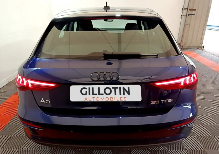 Vue arrière d'une Audi A3 35 TFSI bleu avec feux LED allumés dans un garage fermé.