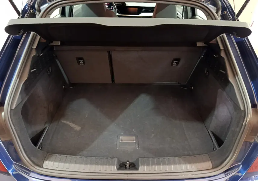 Coffre ouvert vu de l'arrière d'une Audi A3 bleu 2023, montrant l'espace de chargement et la tablette de séparation.