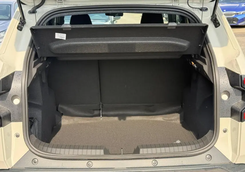 Coffre ouvert vu de l'arrière d'un Dacia Duster gris clair, montrant l'espace de chargement vide et la tablette cache-bagages relevée.