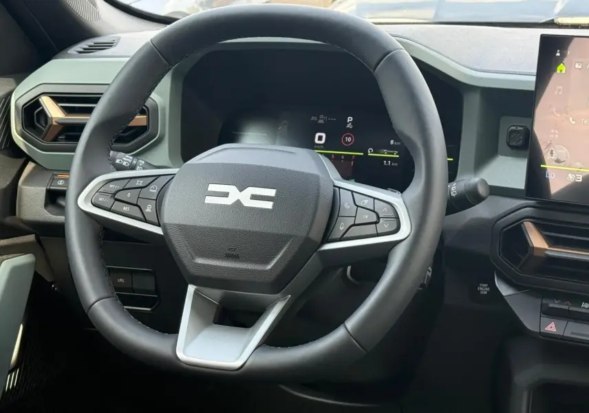 Vue rapprochée du volant multifonction noir et gris du Dacia Duster 2026 avec tableau de bord digital et écran tactile.