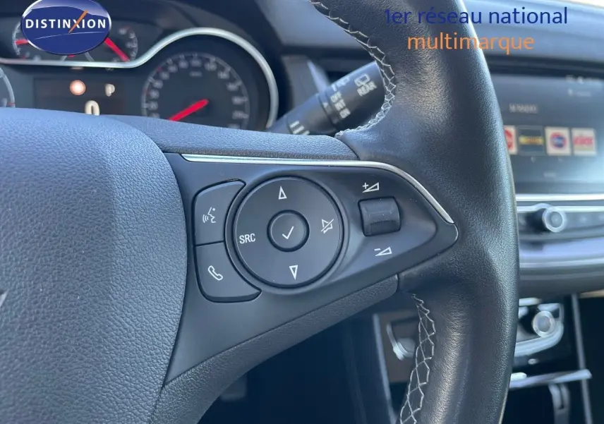 Gros plan sur les commandes au volant en cuir noir de l'Opel Grandland X 2021, avec tableau de bord et écran tactile en arrière-plan.