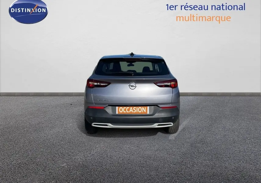 Vue arrière d'un Opel Grandland X gris quartz métal avec plaque "OCCASION" sur fond neutre.