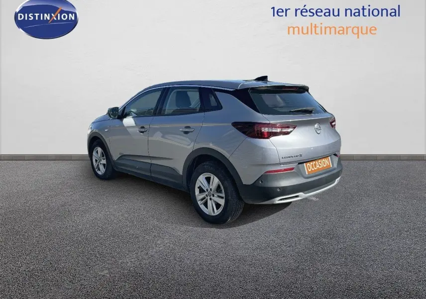 Opel Grandland X gris quartz métal vu en 3/4 arrière droit sur fond neutre avec plaque occasion visible.
