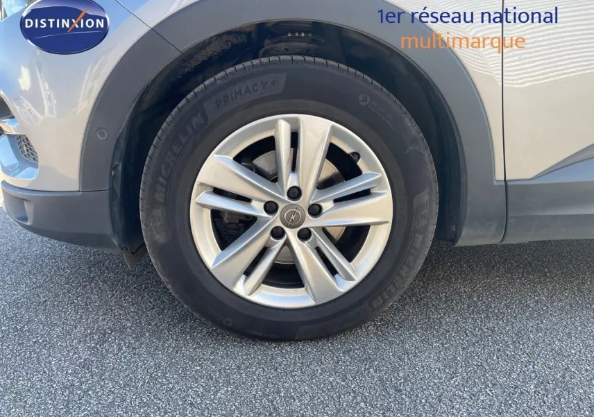 Gros plan sur la roue avant gauche avec jante argentée du SUV Opel Grandland X gris quartz metal.