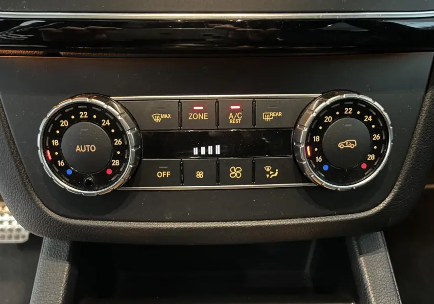 Gros plan sur la commande de climatisation bi-zone du Mercedes GLE Coupé blanc, avec réglages de température et ventilation.