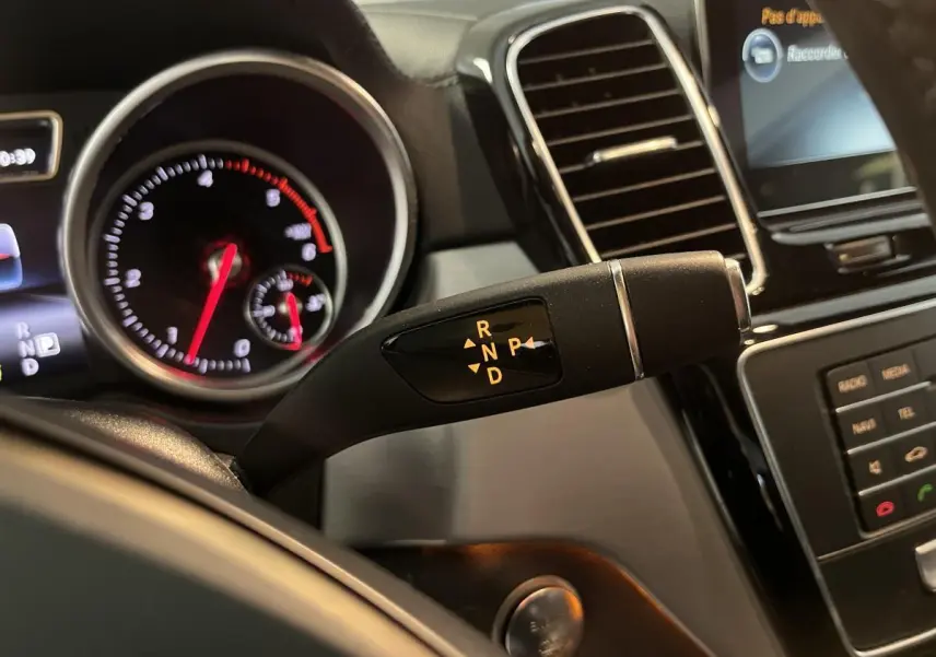 Gros plan sur levier de boîte automatique et tableau de bord noir d'un Mercedes GLE Coupé blanc 2016.