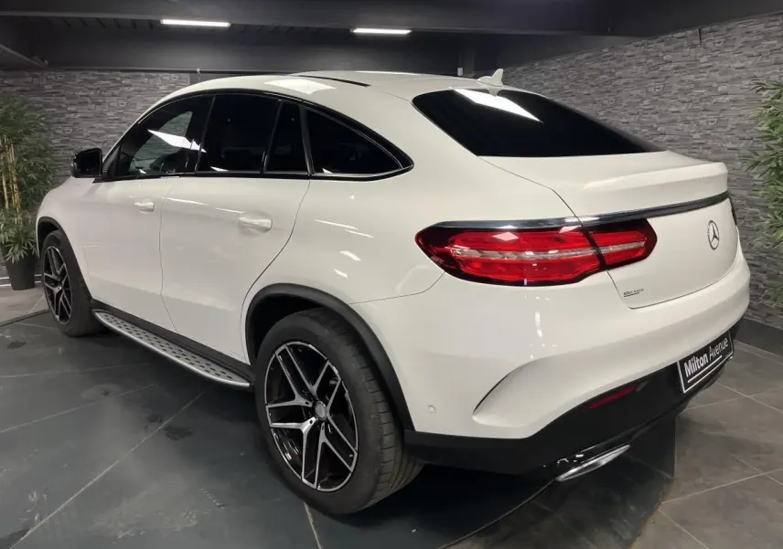Vue 3/4 arrière droite d'un Mercedes GLE Coupé blanc avec jantes AMG noires et toit ouvrant panoramique.