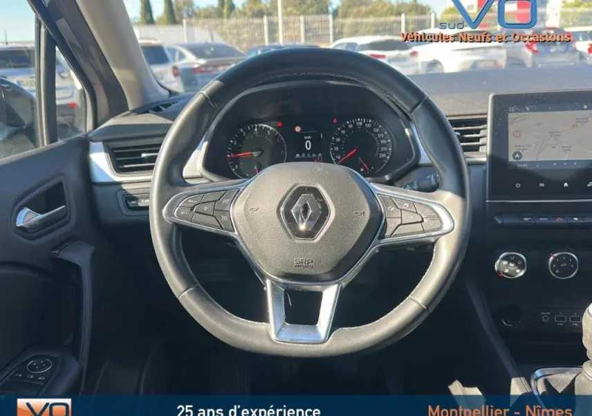 Vue centrée sur le volant noir du Renault Captur gris 2021 avec tableau de bord et écran tactile visible.