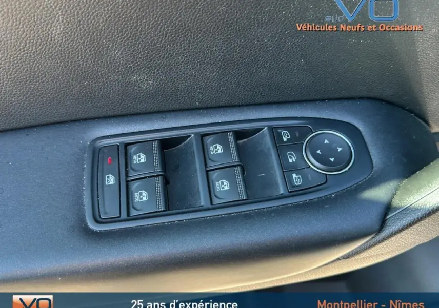 Gros plan sur les commandes des vitres électriques et rétroviseurs sur la porte côté conducteur d'un Renault Captur gris 2021.