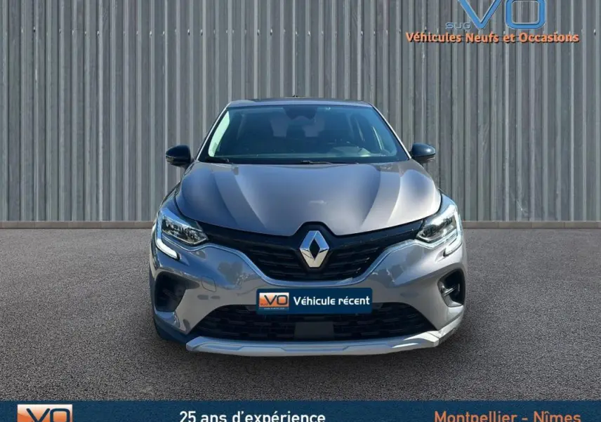 Vue frontale d'un Renault Captur gris 2021 avec feux allumés et logo marqué sur la calandre.