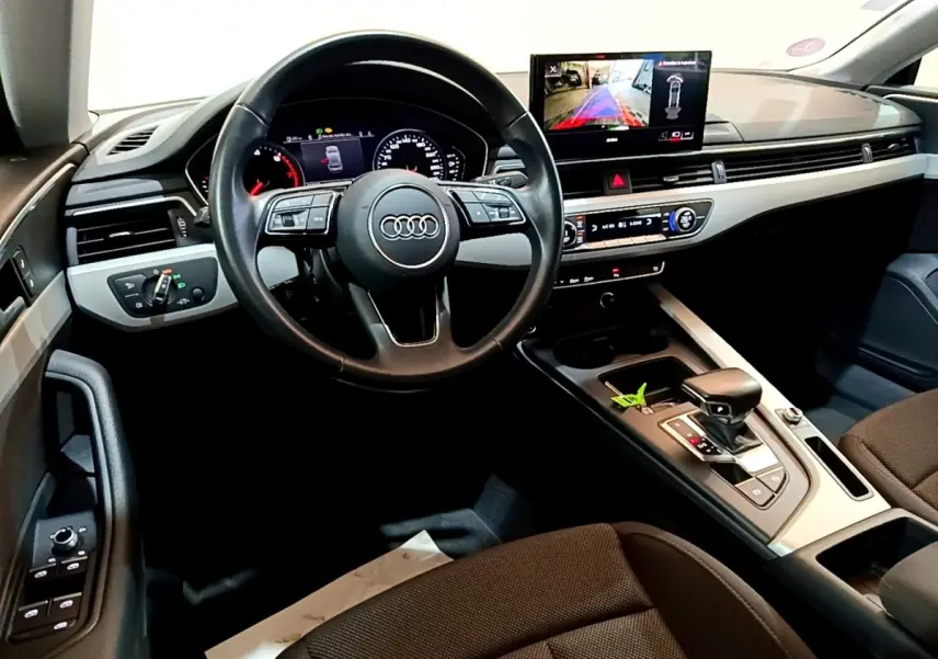 Vue intérieure de l'Audi A5 2021, tableau de bord et volant cuir noir avec écran central affichant la caméra de recul.