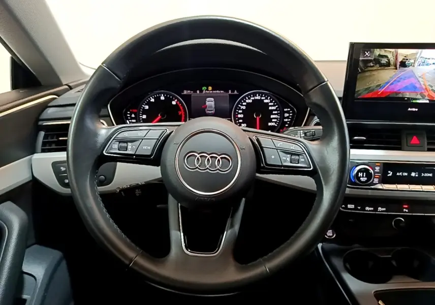 Vue intérieure centrée sur le volant cuir noir d'une Audi A5 35 TFSI 2021 avec tableau de bord digital et écran multimédia.