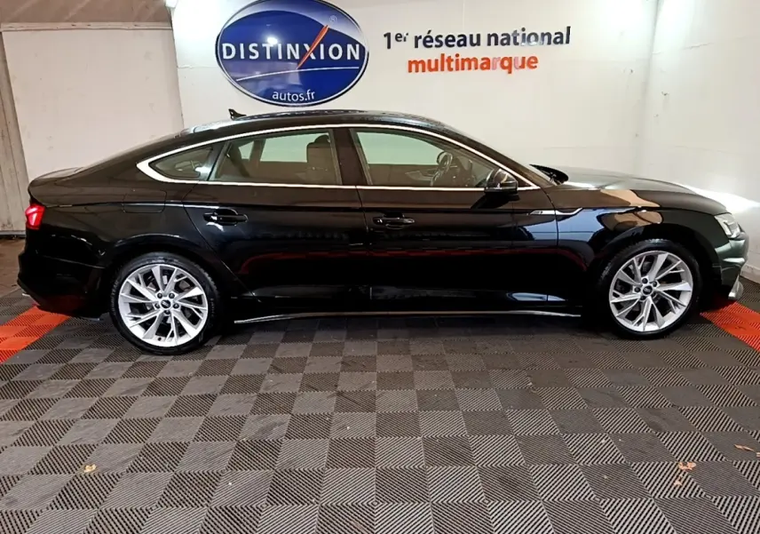 Profil côté gauche d'une Audi A5 noire 2021, élégante avec jantes alliage et lignes fluides dans un showroom.