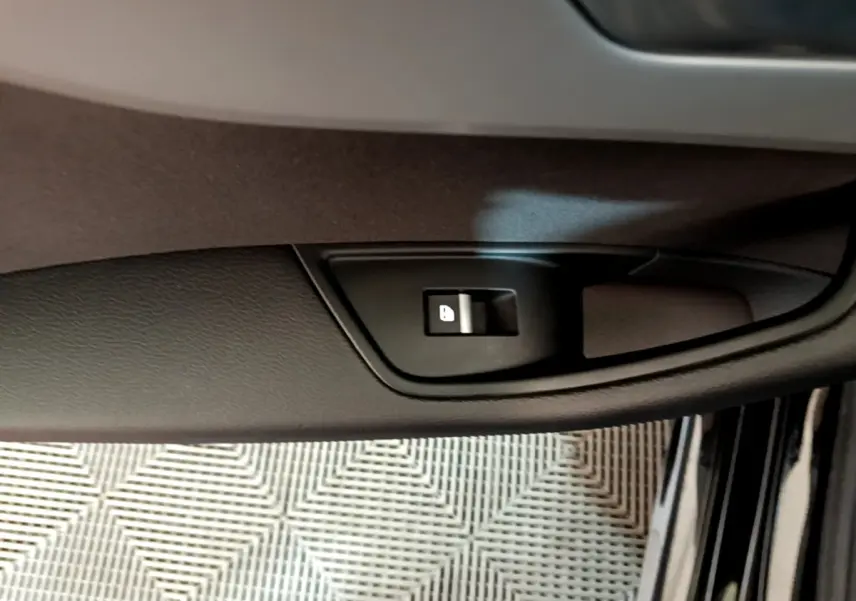 Gros plan sur le bouton de verrouillage de porte côté conducteur d'une Audi A5 noire, intérieur visible.