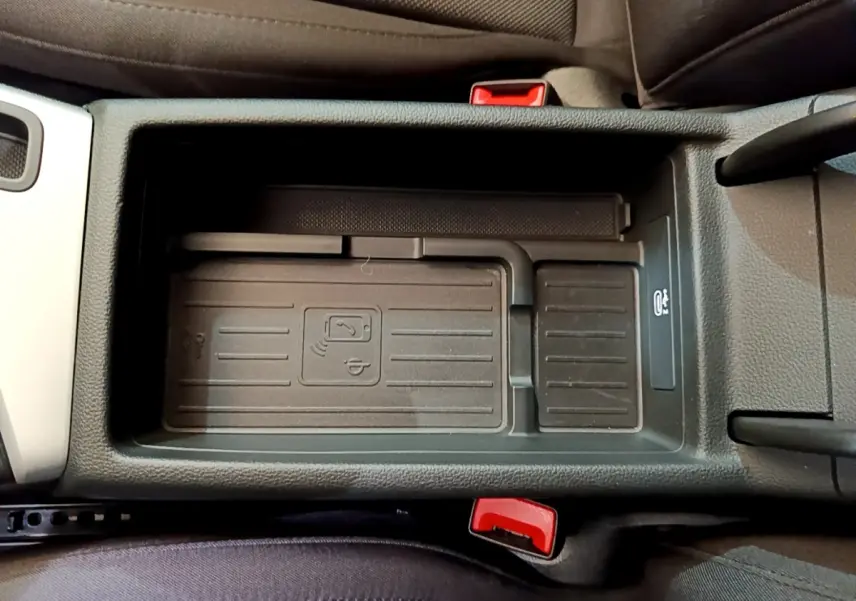 Vue plongeante sur le compartiment central noir de l'Audi A5 35 TFSI 2021, avec indication de charge sans fil et ceintures rouges.