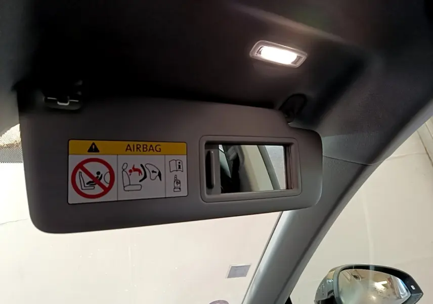 Détail du pare-soleil côté conducteur avec miroir et avertissement airbag dans l'Audi A5 noire de 2021.