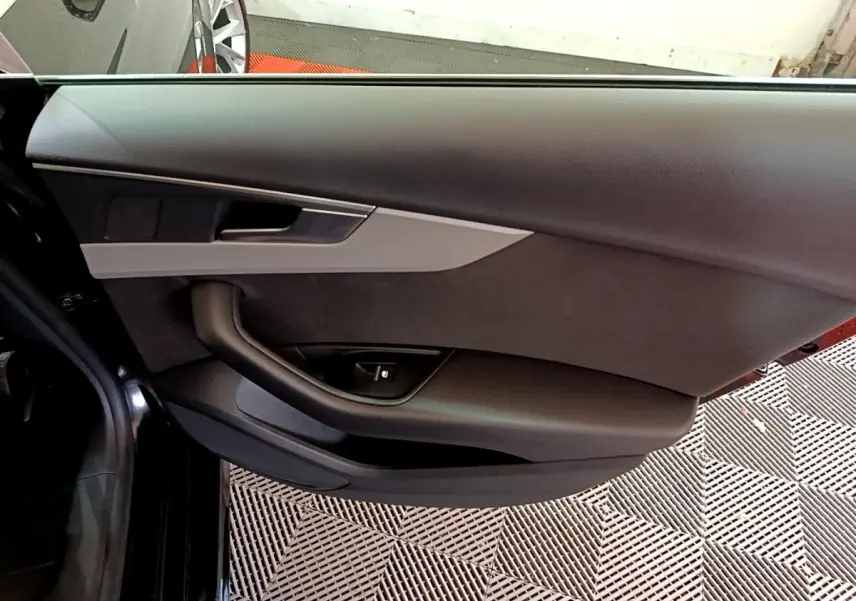 Porte intérieure côté gauche noire de l'Audi A5 35 TFSI 2021 avec poignée argentée et commande de vitre électrique.