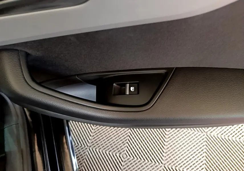 Bouton de verrouillage centralisé sur la portière côté gauche d'une Audi A5 noire, vue en gros plan intérieur.