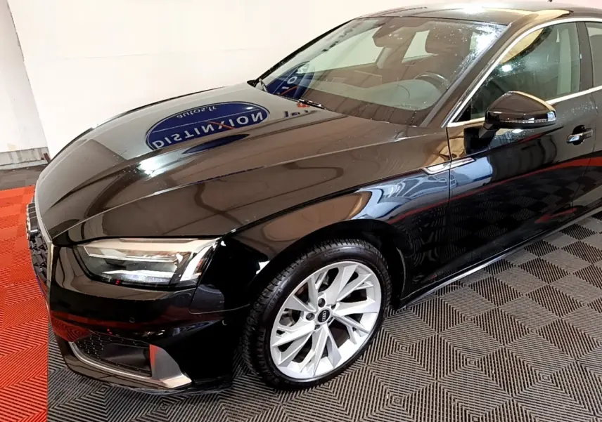 Audi A5 noir vue 3/4 avant droit, mettant en valeur ses jantes argentées et ses phares LED modernes.